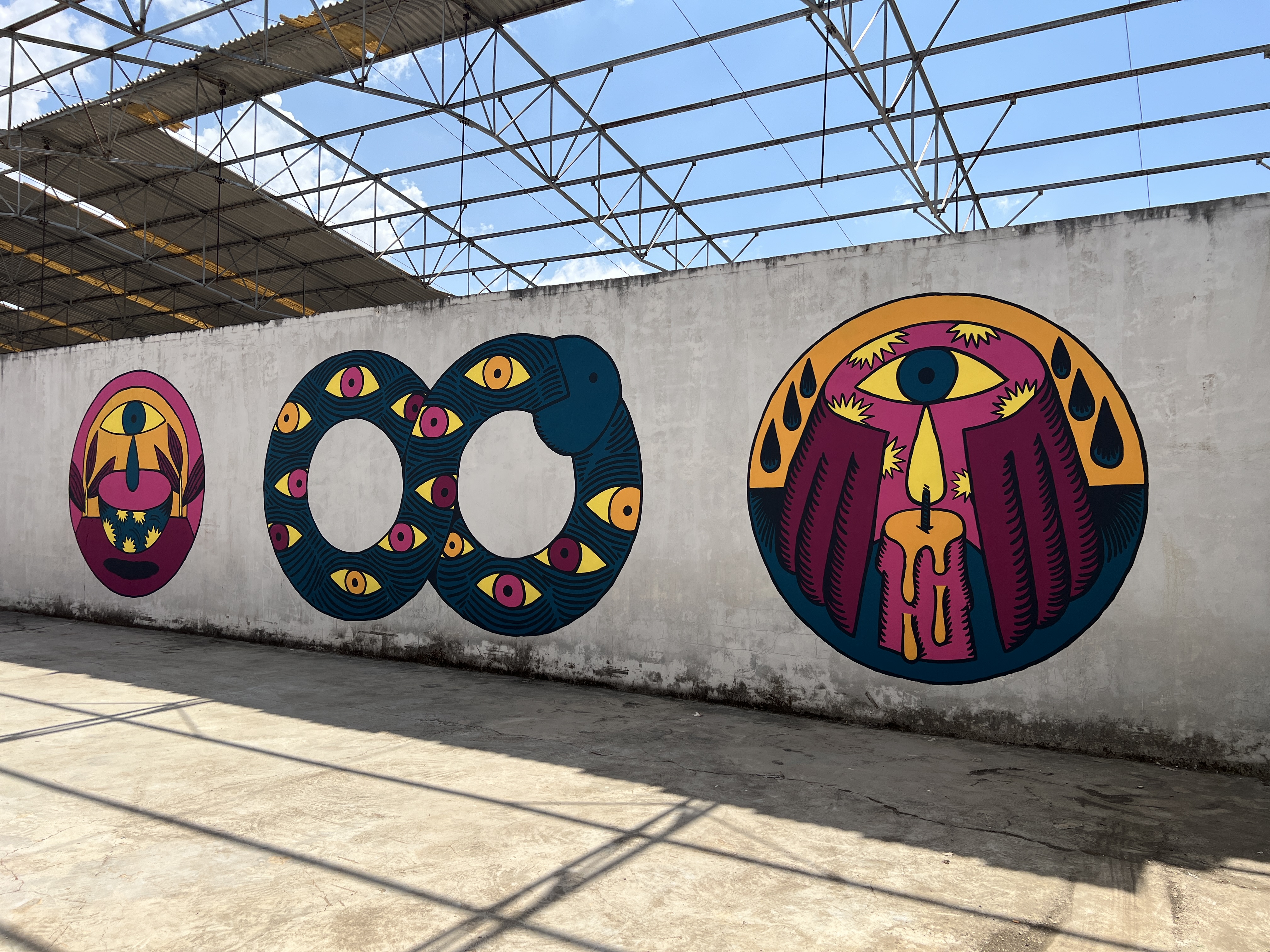 Mural paintings on concrete walls in an abandoned factory in Pyrgos Ilia, Greece, 2025 -- symbolic motifs of eyes, flames and water